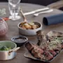 Grillattu pihvi, jonka päällä on ituja, suorakulmaisella mustalla lautasella puupöydällä, ympärillä kastiketta, parsakaalia, perunoita ja lasi.