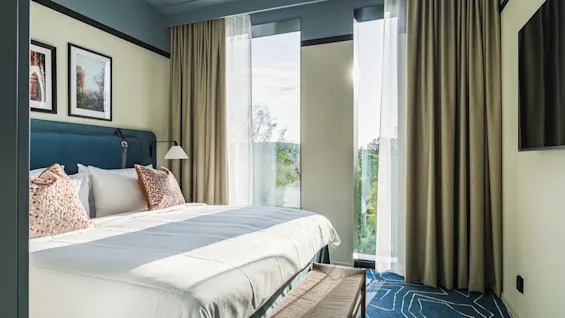 A bright and inviting hotel room at Hernö Gin Hotel with a comfortable bed, large windows, and a serene view of nature.