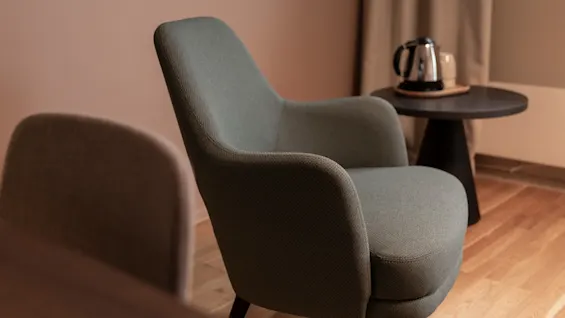 An inviting green armchair next to a small table with a kettle, suggesting a comfortable break.