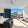Et lyst, moderne hotelværelse med to enkeltsenge, et stort vindue med udsigt over byen og et behageligt siddeområde.