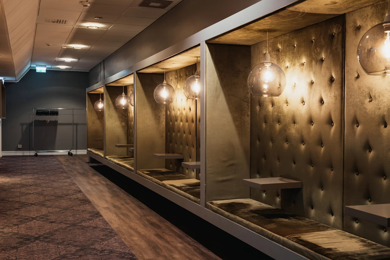 Mysiga privata sittbås med tuftad klädsel och hängande lampor i en korridor på Home Hotel Grand, Helsingborg.