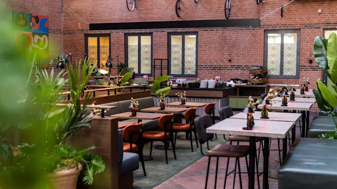 A stylish hotel restaurant at Comfort Hotel Vesterbro featuring brick walls, eclectic seating, green plants, and decorative bicycles.