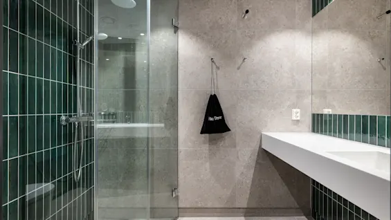 Et moderne og rent bad med glassdusj, elegant vask og en pose merket Hair Dryer på veggen.