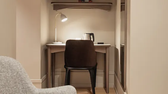 En välbelyst personlig arbetsplats med skrivbord, stol och vattenkokare, utformad för produktivitet eller en lugn stund.