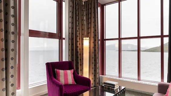 Mukava istuinalue eloisalla violetilla tuolilla, josta avautuu laaja näkymä rauhalliselle järvelle ja vuorille.