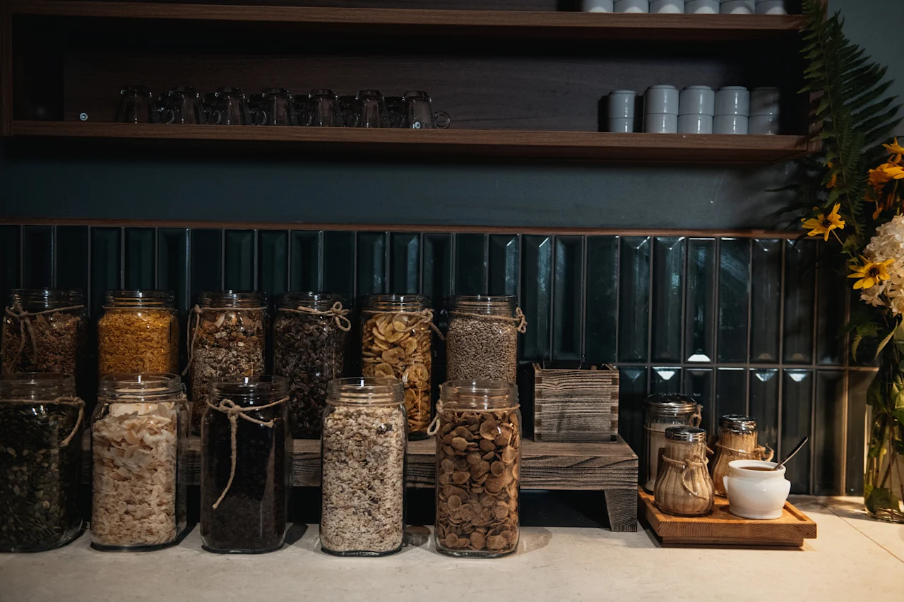 En självserveringsfrukostbar med olika flingor och gryn i glasburkar, tillsammans med en liten kaffe- eller testation.