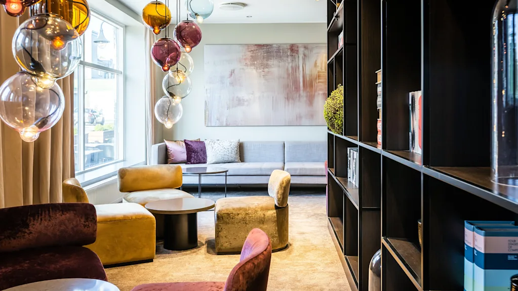 A stylish and inviting lounge area with colorful globe lights, comfortable seating, and a large window, perfect for relaxation.