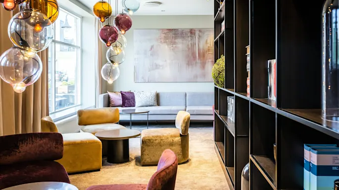 A stylish and inviting lounge area with colorful globe lights, comfortable seating, and a large window, perfect for relaxation.