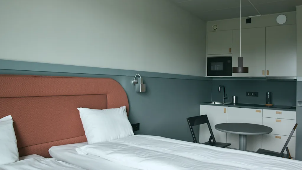 Ett modernt och funktionellt hotellrum på Stopover Hotel Falkenberg med en bekväm säng och ett kompakt pentry.
