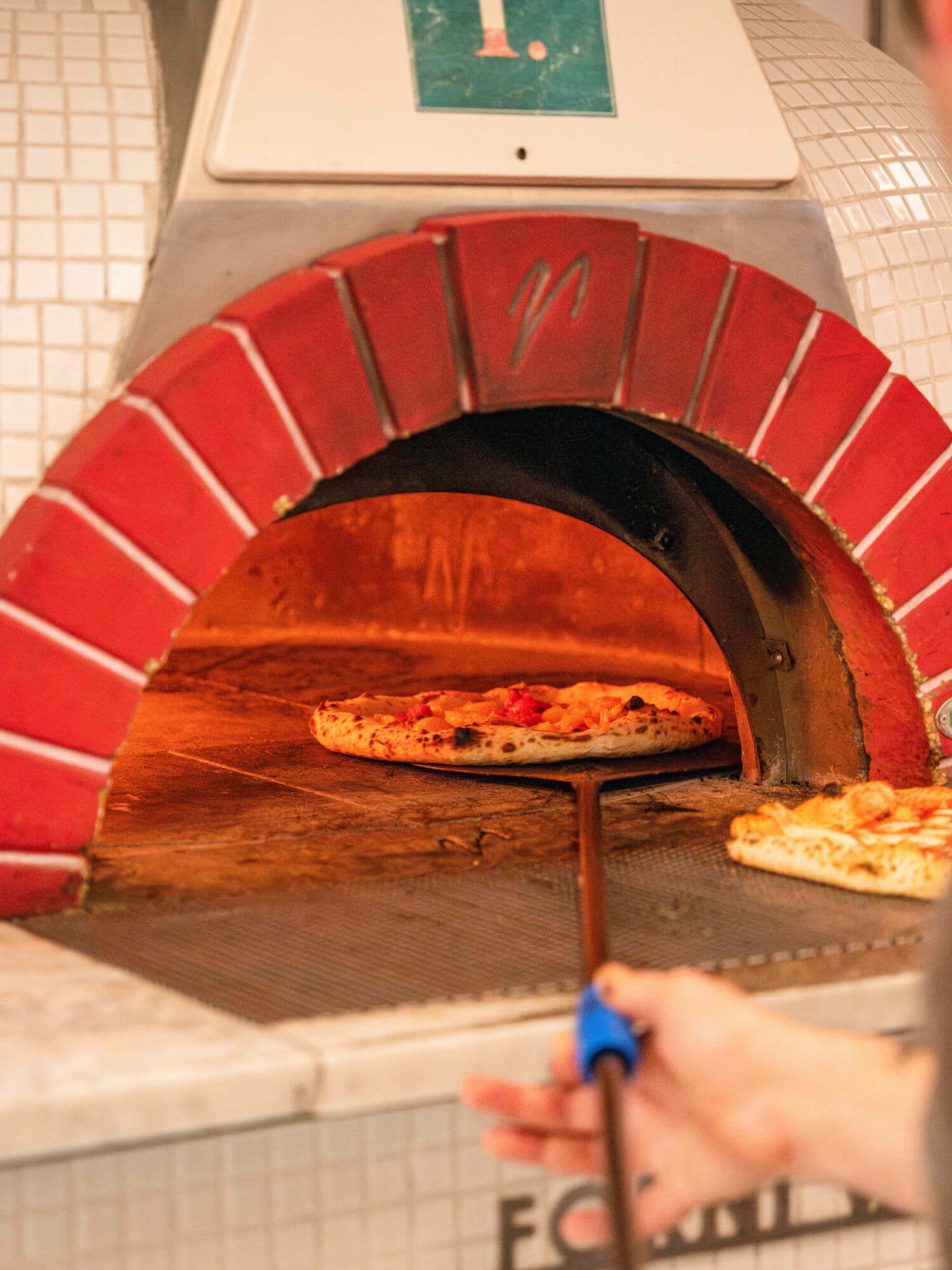 Pizza chef putting a pizza in the oven.