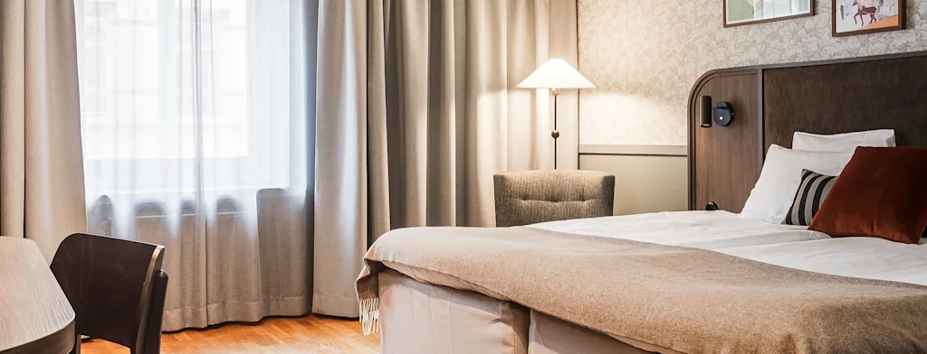 Ett bekvämt och inbjudande hotellrum med en säng, ett skrivbord och ett fönster, vilket antyder en avkopplande vistelse.