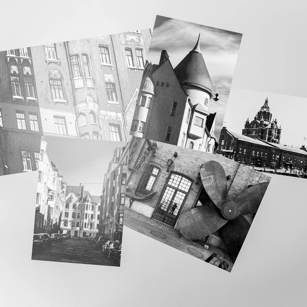 Several black and white photos of buildings and architectural details are scattered on a white surface.
