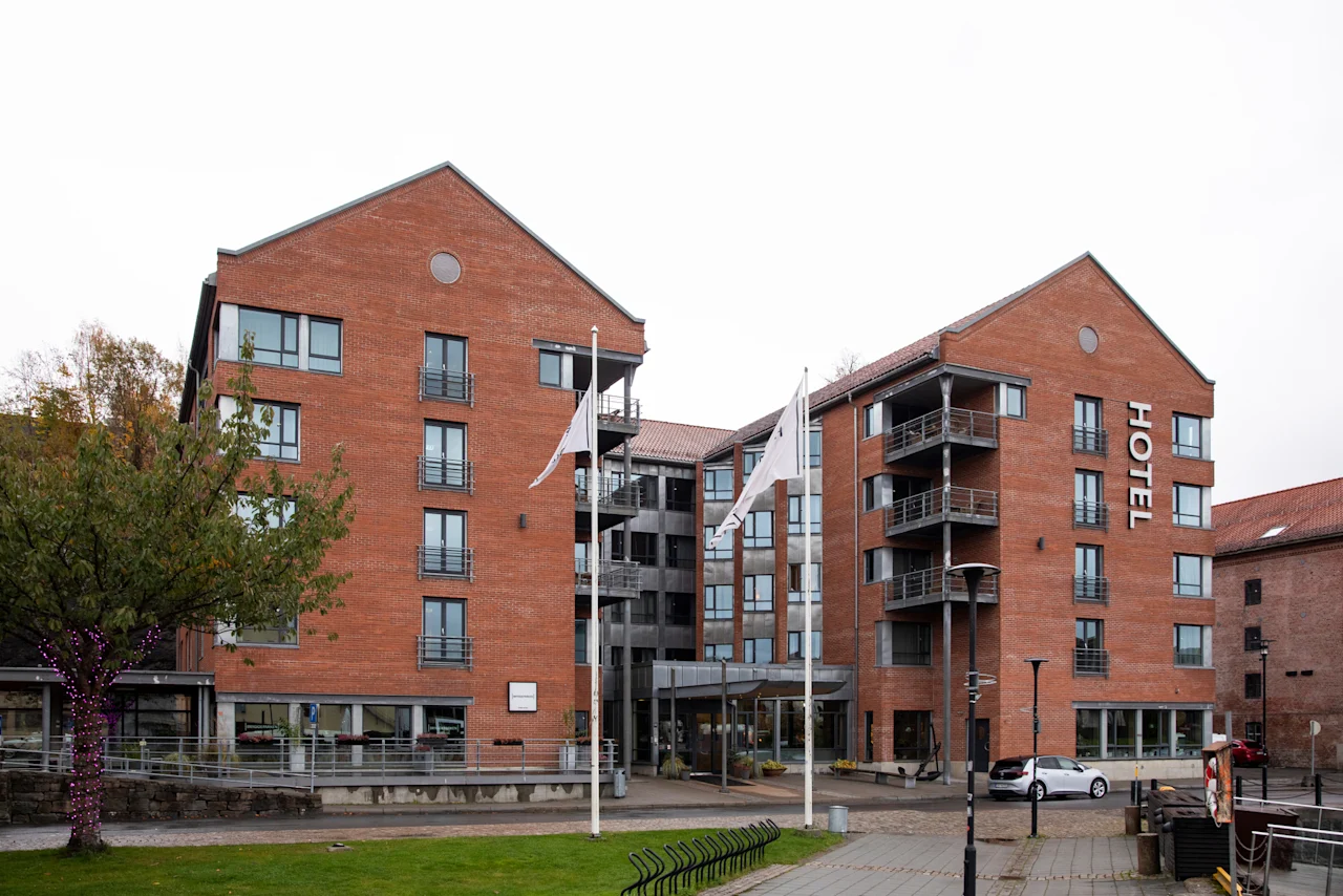 A modern brick hotel building with balconies and large windows, featuring a prominent "HOTEL" sign.