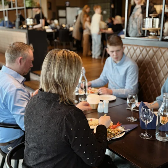 Folk som nyter et måltid sammen i en livlig restaurant.