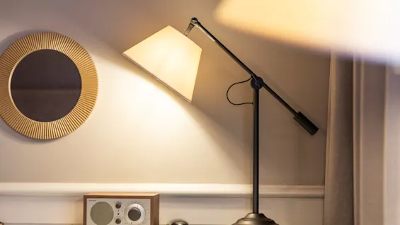 A warm, inviting desk area at Home Hotel Grand Bodø, featuring a stylish lamp, a classic radio, and a decorative mirror.