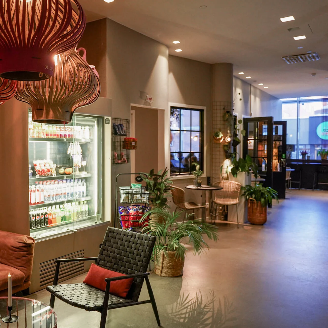 En hyggelig lounge med dekorativ belysning, komfortable siddepladser og et drikkekøleskab i et indendørs miljø.