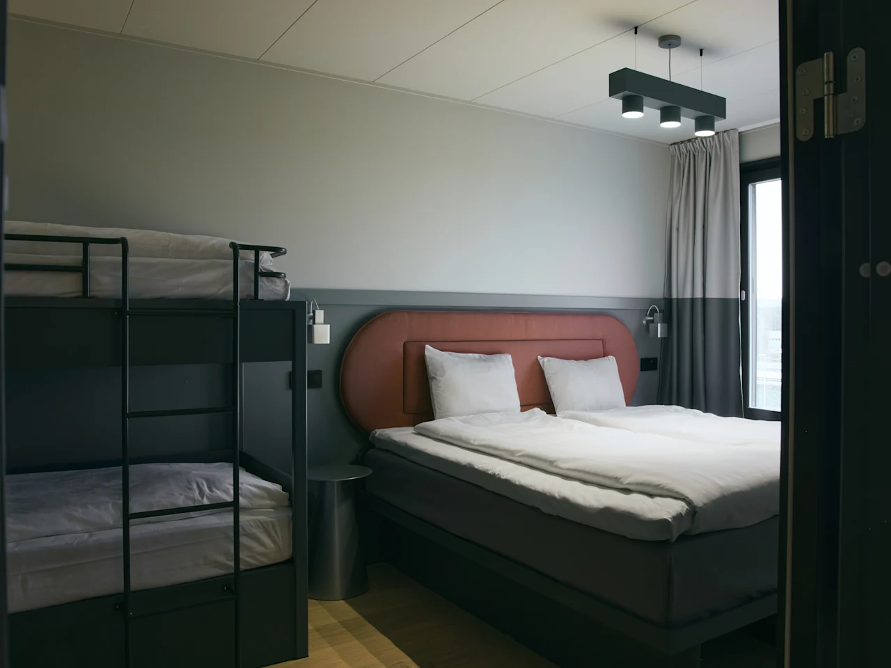 Ett modernt hotellrum på Stopover Hotel Falkenberg med en bekväm dubbelsäng och en våningssäng, perfekt för familjer.
