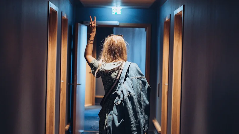 En ung kvinna går genom en hotellkorridor med ryggen mot kameran.