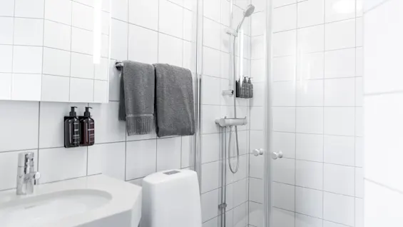 Puhdas ja kutsuva moderni kylpyhuone, käyttövalmis, suihkulla, pesualtaalla ja puhtailla pyyhkeillä.