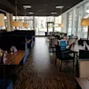 A modern restaurant dining area with set tables, comfortable seating, and large windows offering natural light.