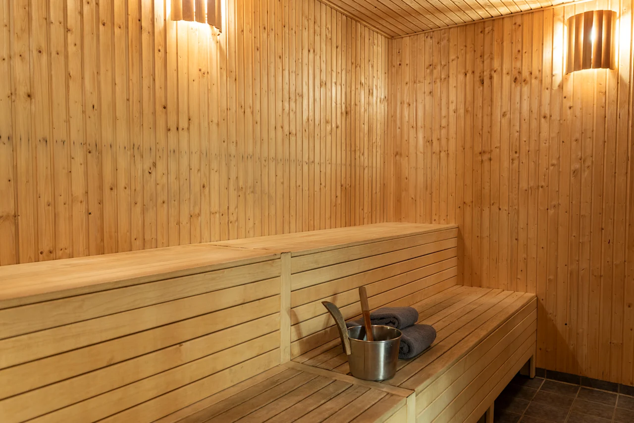 Viihtyisä puusauna pehmeällä valaistuksella, penkeillä ja tarvikkeilla virkistävää höyryhetkeä varten. 🧖‍♀️