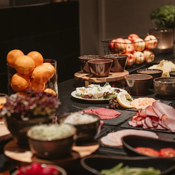 En härlig buffé med färsk frukt, charkuterier och ostar på Home Hotel Wellington, redo för gästerna att njuta av.