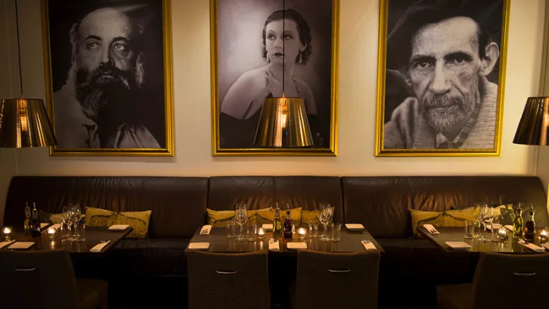 Matsal med bord, stolar och porträttfotografier på Clarion Collection® Hotell Drott.