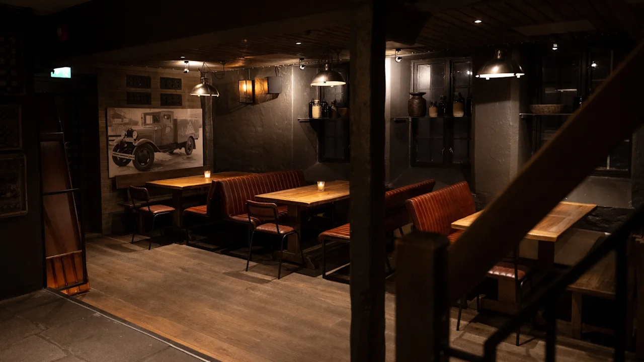 Et dunkelt belyst, koselig restaurantinteriør med trebord, båser og et kunstverk av en veteranlastebil på veggen.