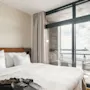 A comfortable hotel room at Farris Bad in Larvik with a bed, slippers, and a robe, featuring a balcony overlooking the sea.