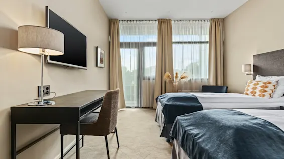 Ett ljust och inbjudande hotellrum på Quality Hotel Ulstein med två bekväma sängar, ett skrivbord och ett stort fönster.