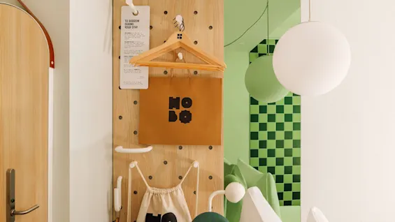 A pegboard wall in a hobo oslo room with a tag reading TO BORROW DURING YOUR STAY, a paper bag, and a drawstring bag.