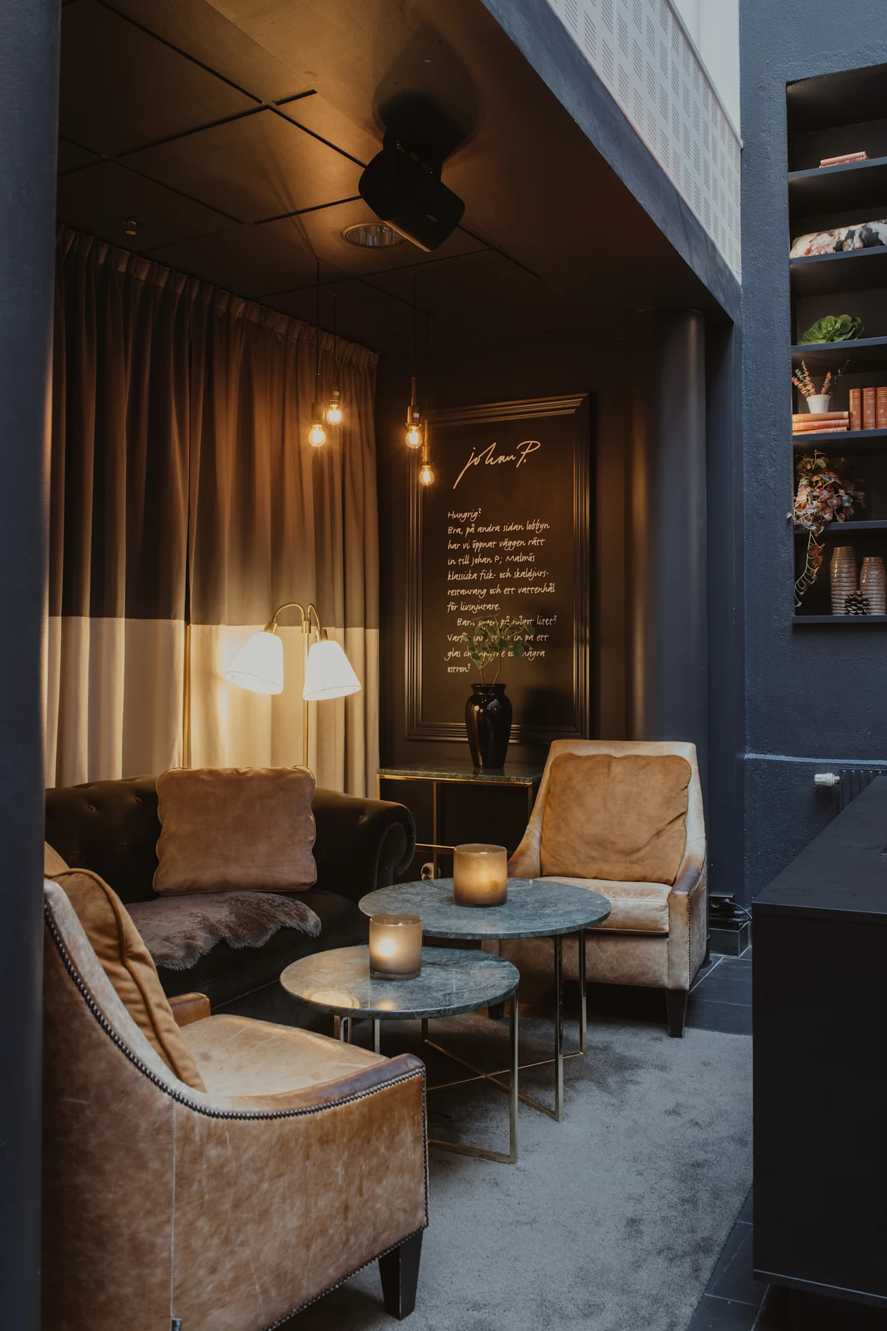Et hyggeligt loungeområde med varm belysning og komfortable siddepladser. Et skilt lyder: Sulten? Godt, på den anden side af lobbyen har vi åbnet væggen lige ind til restauranten.