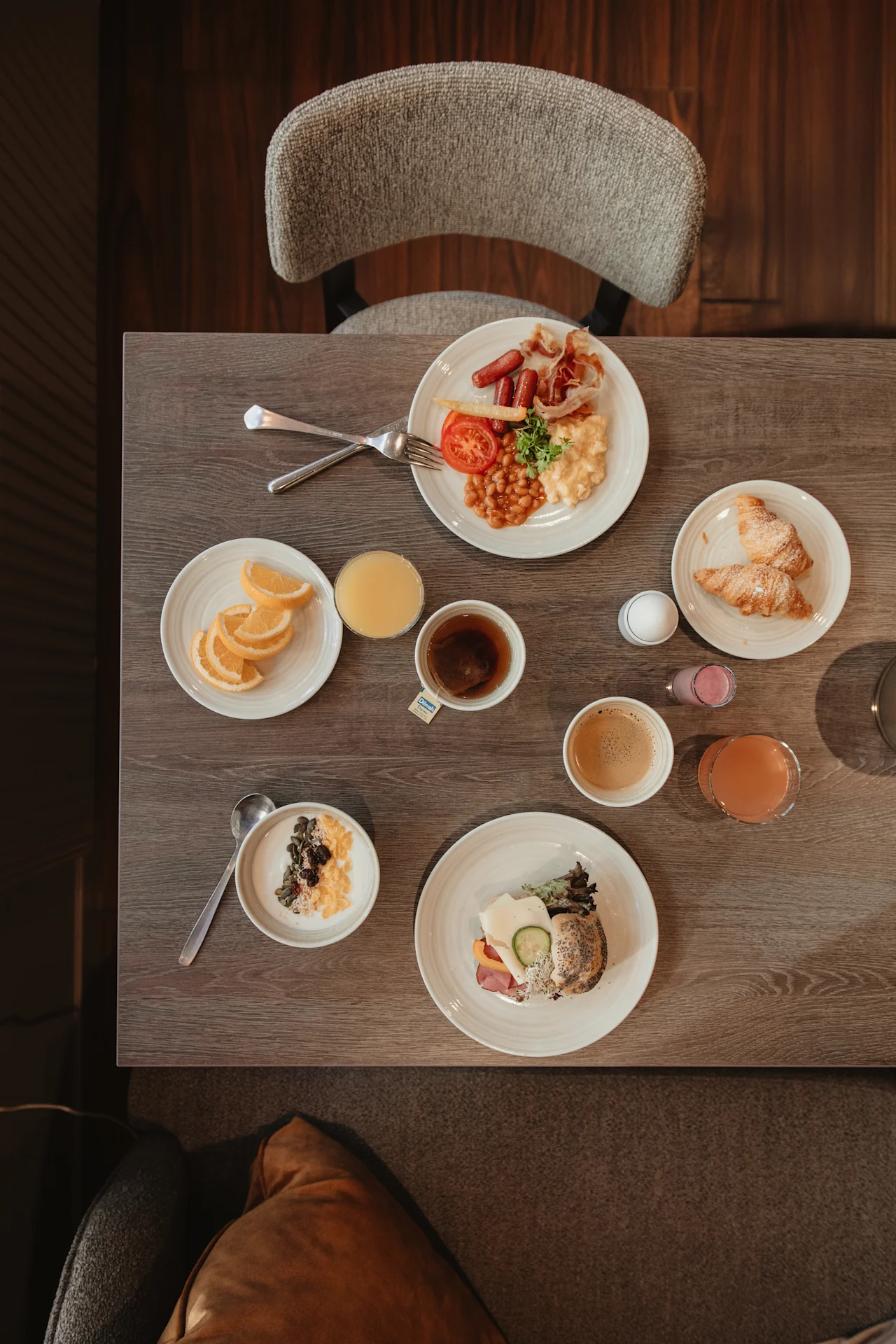 Ett bord dukat med en varierad frukostbuffé, inklusive varma rätter, bakverk, frukt, yoghurt och olika drycker.