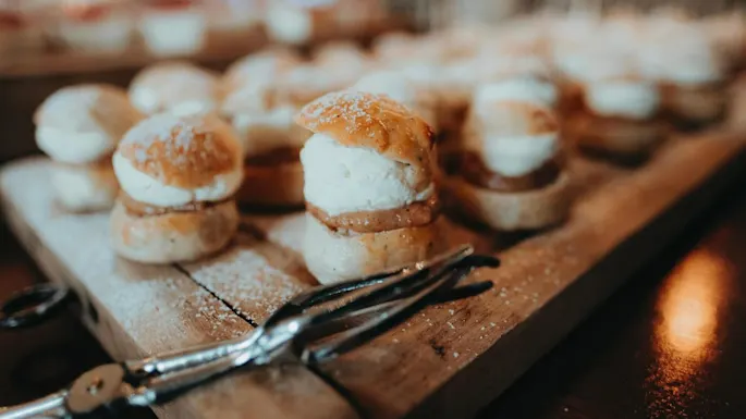 Cream-filled pastries dusted with powdered sugar, arranged on a wooden board.