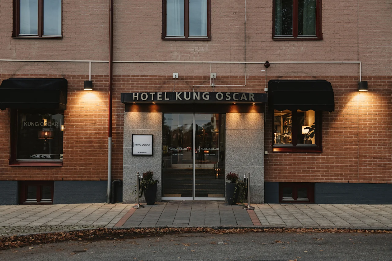 The illuminated entrance of Hotel Kung Oscar Home Hotel, a welcoming brick building with glass doors. add Home Hotel Kung Oscar.