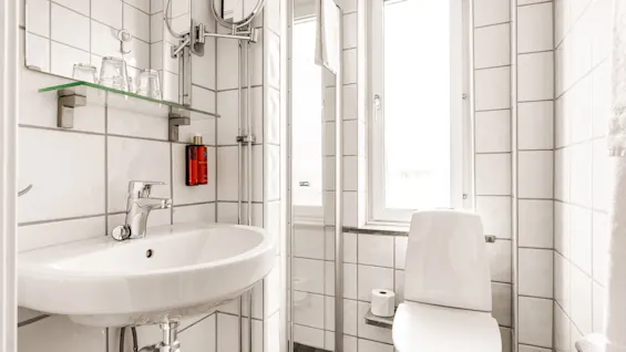 Valoisa, moderni kylpyhuone Comfort Hotel Linköping Cityssä, jossa on pesuallas, wc ja suihkutila, valkoisilla laatoilla.