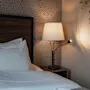 A warm and inviting bedroom with a bed, a patterned wall, and two lamps illuminating the space.