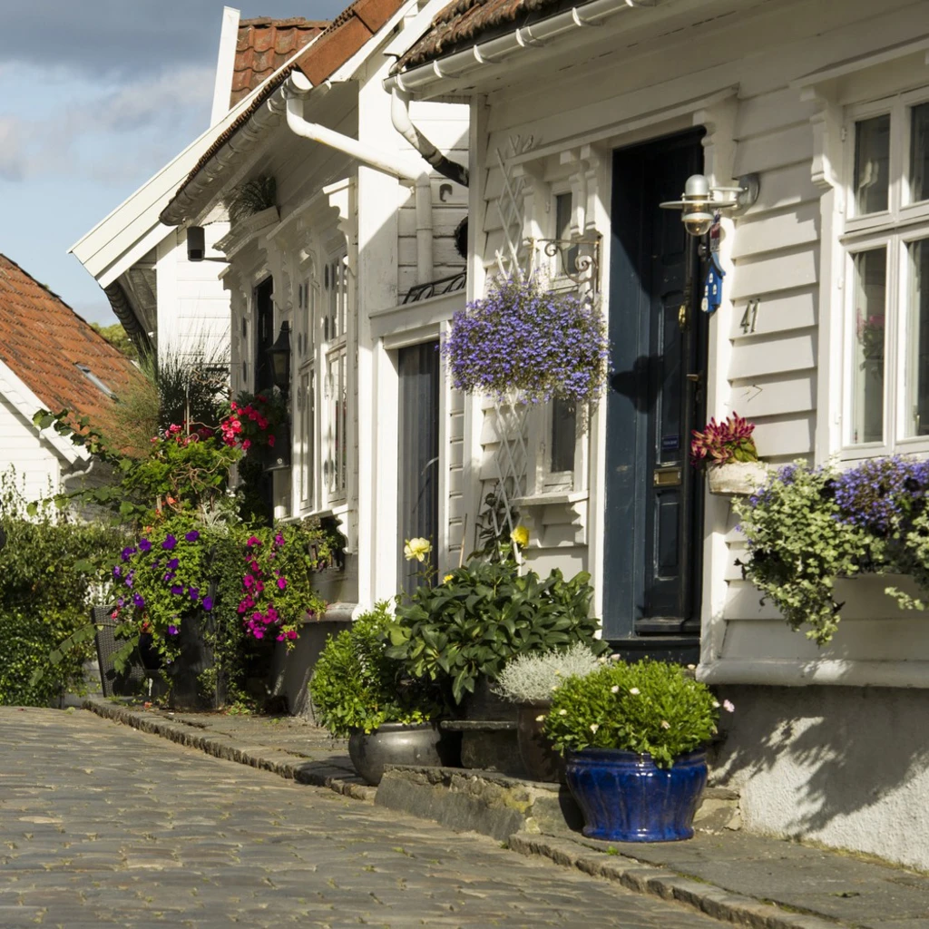 Gamla stan i Stavanger med vitmålade trähus och blomstrande rabatter.