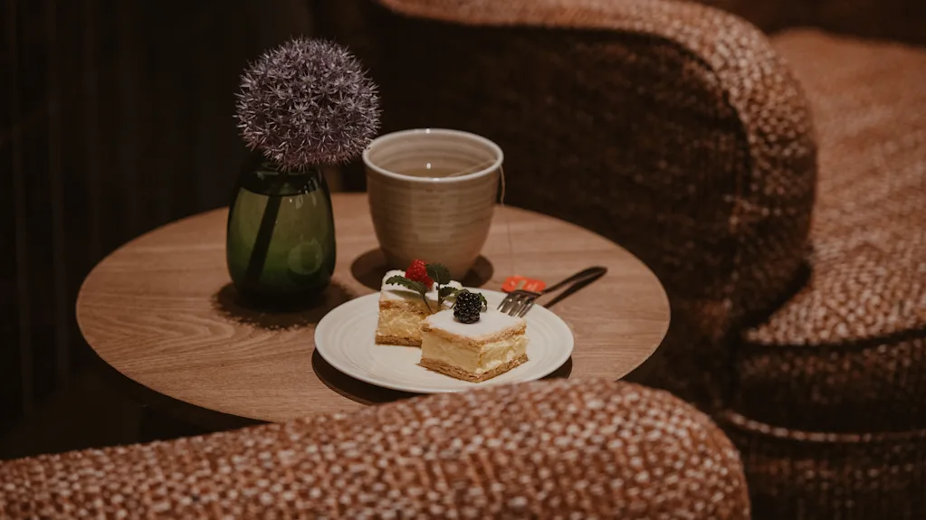 A delightful moment with cake and a hot beverage on a small table, surrounded by plush seating.
