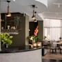 Kutsuva hotellilounge, jossa on tyylikäs baari ja ruokailutila lämpimällä valaistuksella ja mukavilla istuimilla.