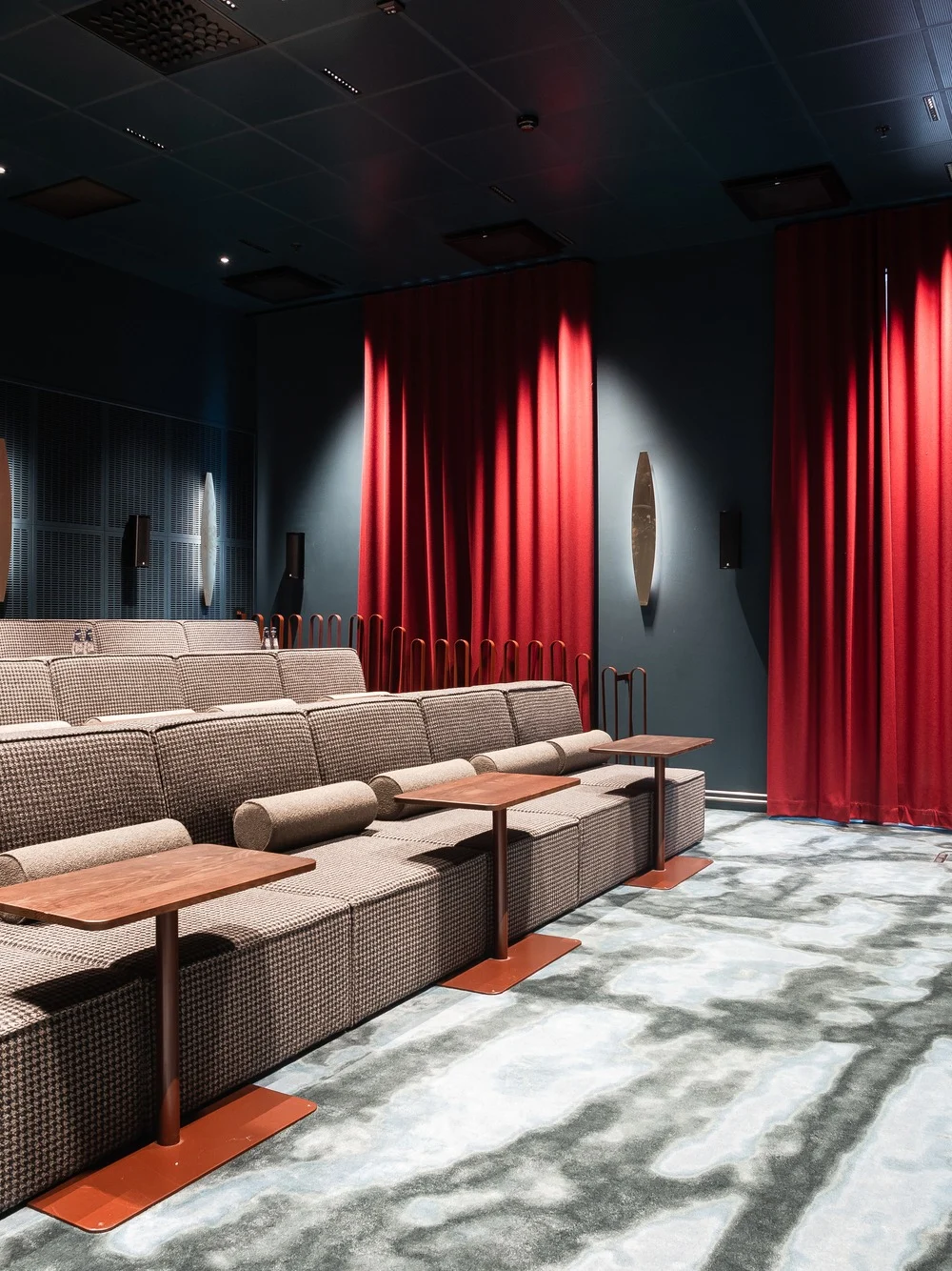 A cozy private cinema with tiered seating, individual tables, and a large screen, ready for a movie experience.