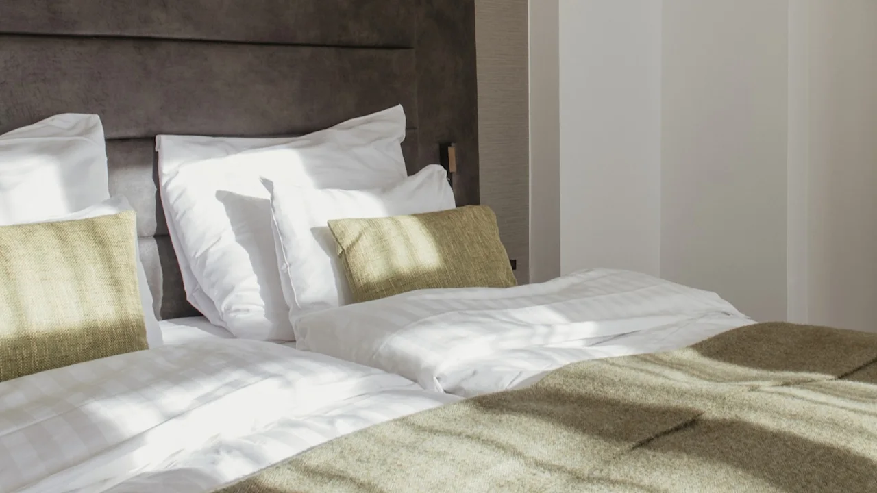 Ett ljust och inbjudande hotellrum med två sängar och en mysig grön filt, som leder in till ett bekvämt vardagsrum.