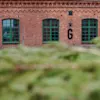 Rød murstensbygning med grønne vinduer i Tandsticksomradet i Jonkoping med bogstavet G på væggen.