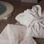 En mysig vit badrock och en fräsch handduk ligger redo bredvid en varm, inbjudande bubbelpool.