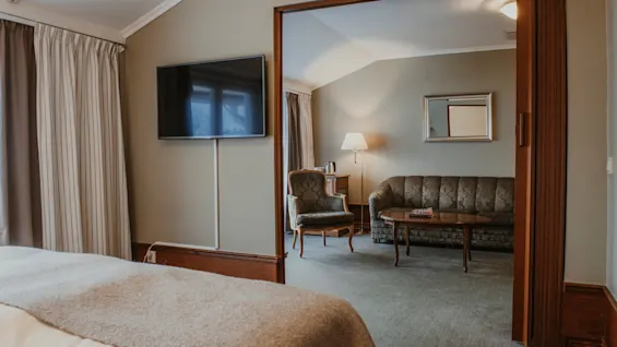 En bekväm hotellsvit med ett sovrum och ett angränsande vardagsrum, perfekt för avkoppling.