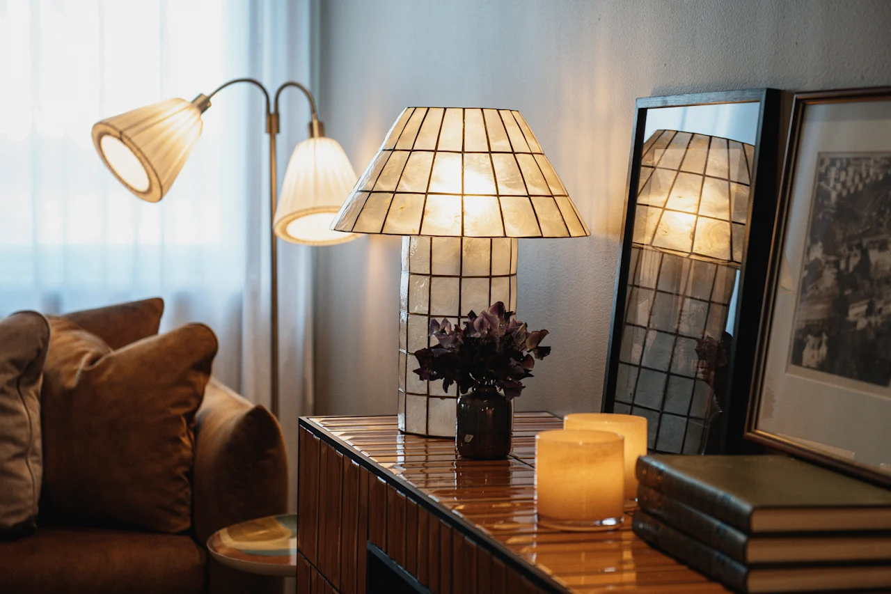 Ett varmt och inbjudande rum med mjuk belysning från lampor, en bekväm soffa och dekorativa föremål på en träyta.