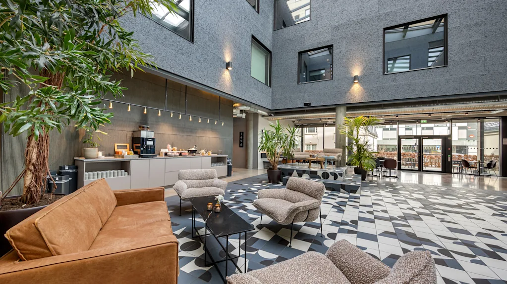 Moderne og innbydende lobby på Comfort Hotel Porsgrunn med komfortable sitteplasser, planter og forfriskningsstasjon.