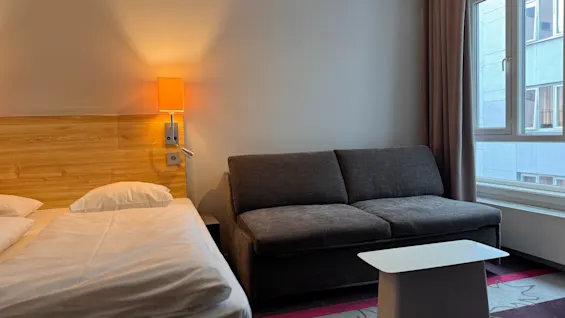 Et koselig hotellrom med en komfortabel seng, en sofa og et vindu, ideelt for et avslappende opphold.