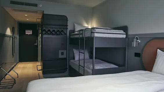 Ett modernt hotellrum på Stopover Hotel Falkenberg med en våningssäng och en dubbelsäng, redo för en bekväm vistelse.