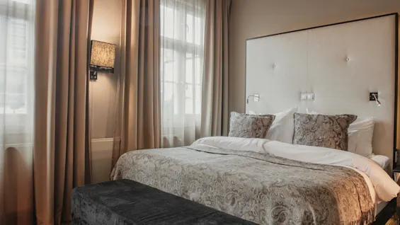 A comfortable and elegantly decorated hotel room with a large bed, soft lighting, and inviting textiles.